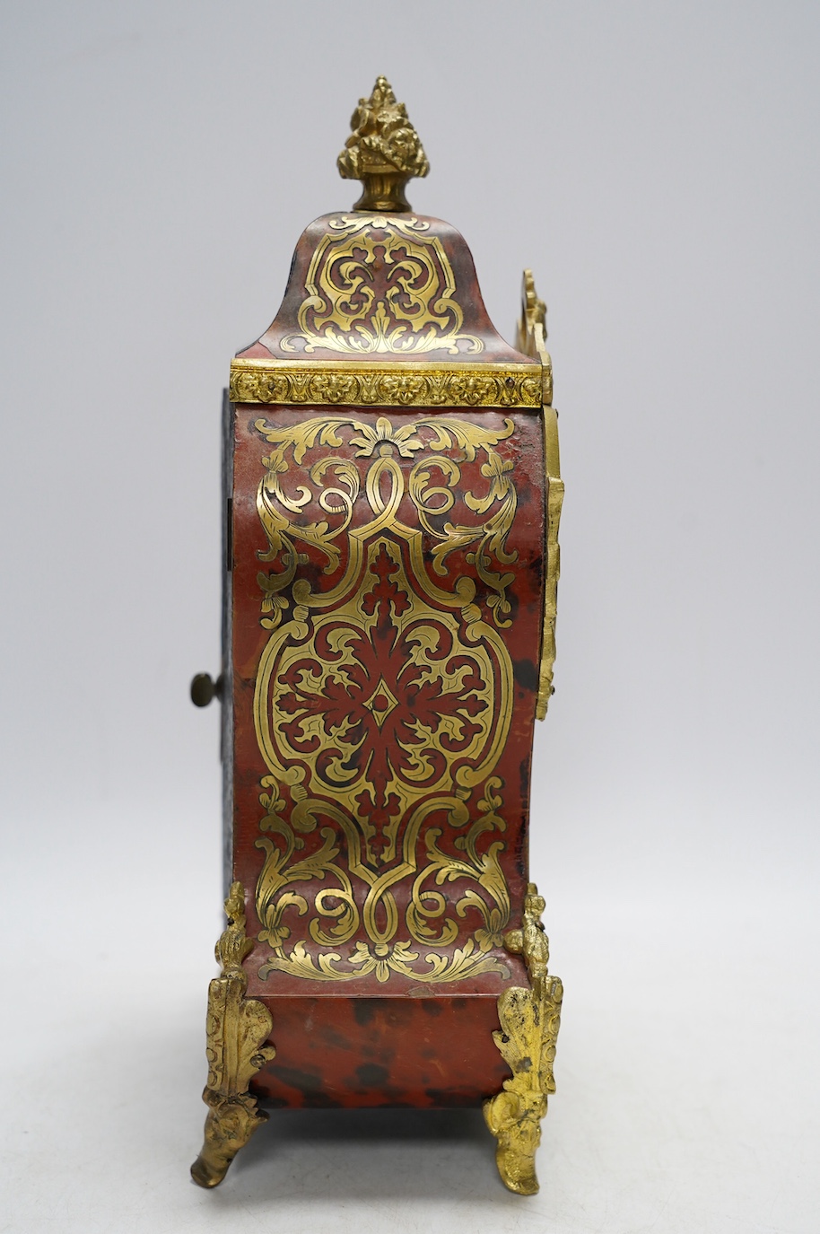 A Louis XV style red boulle eight day mantel clock, with bracket and pendulum, clock 30cm high. Condition - fair, not tested